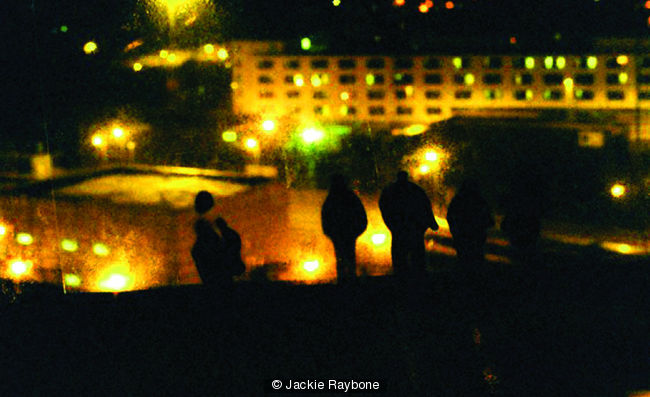 photograph of figures on acetate, stuck to a window and re-photographed on my window with view of city landscape at night